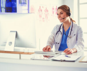 Young practitioner doctor working at the clinic reception desk, she is answering phone calls and scheduling appointments
